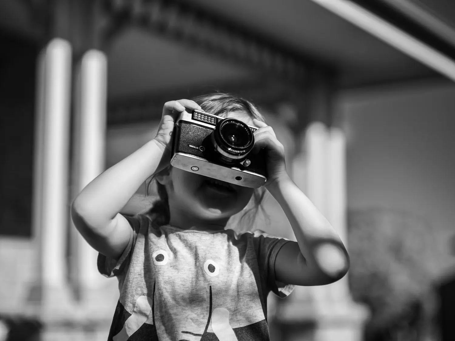 Black and white image of a girl holding a vintage camera