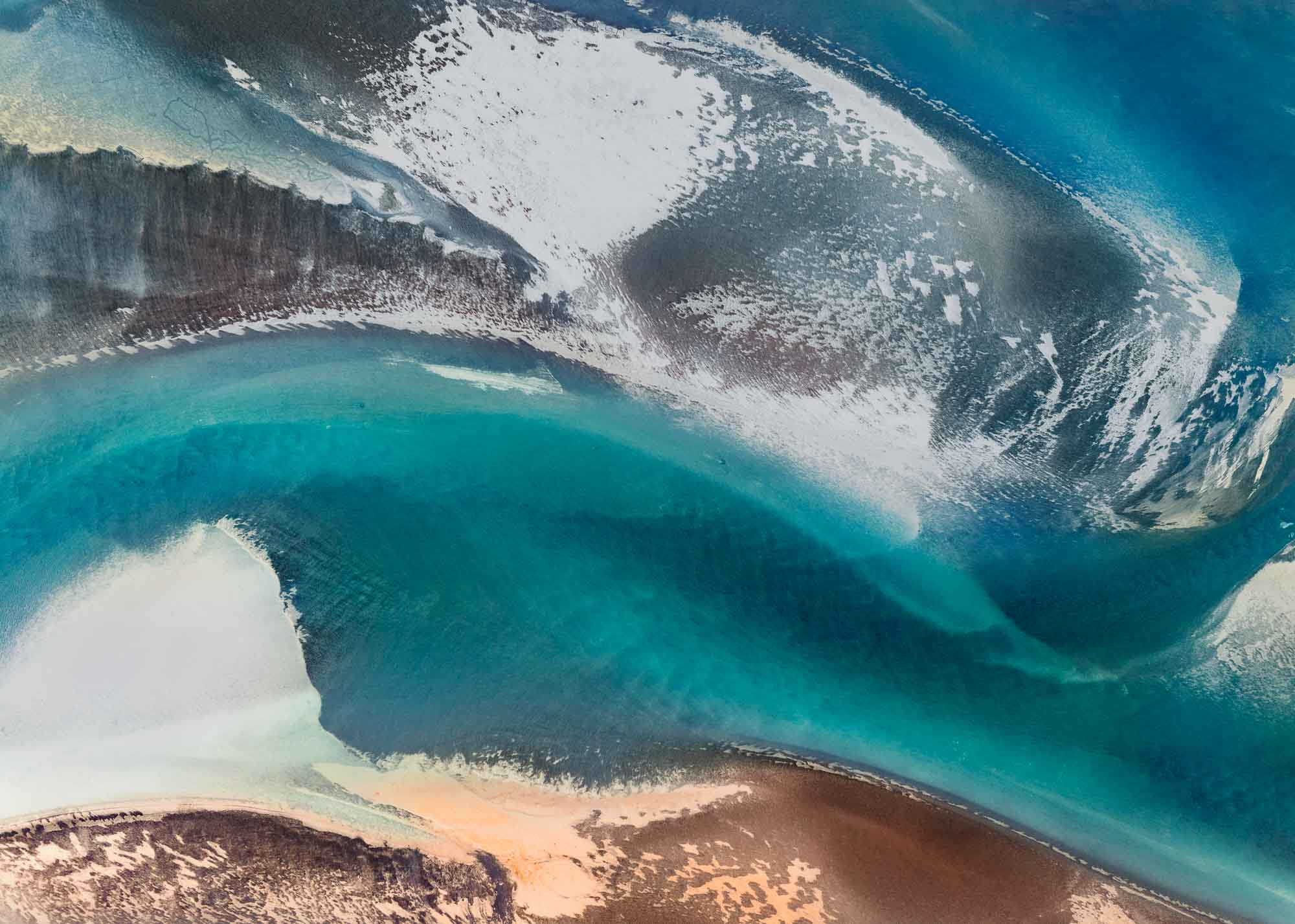 Aerial view of a stunning natural color palette in Iceland with shades of blue, white, and brown in an abstract composition.