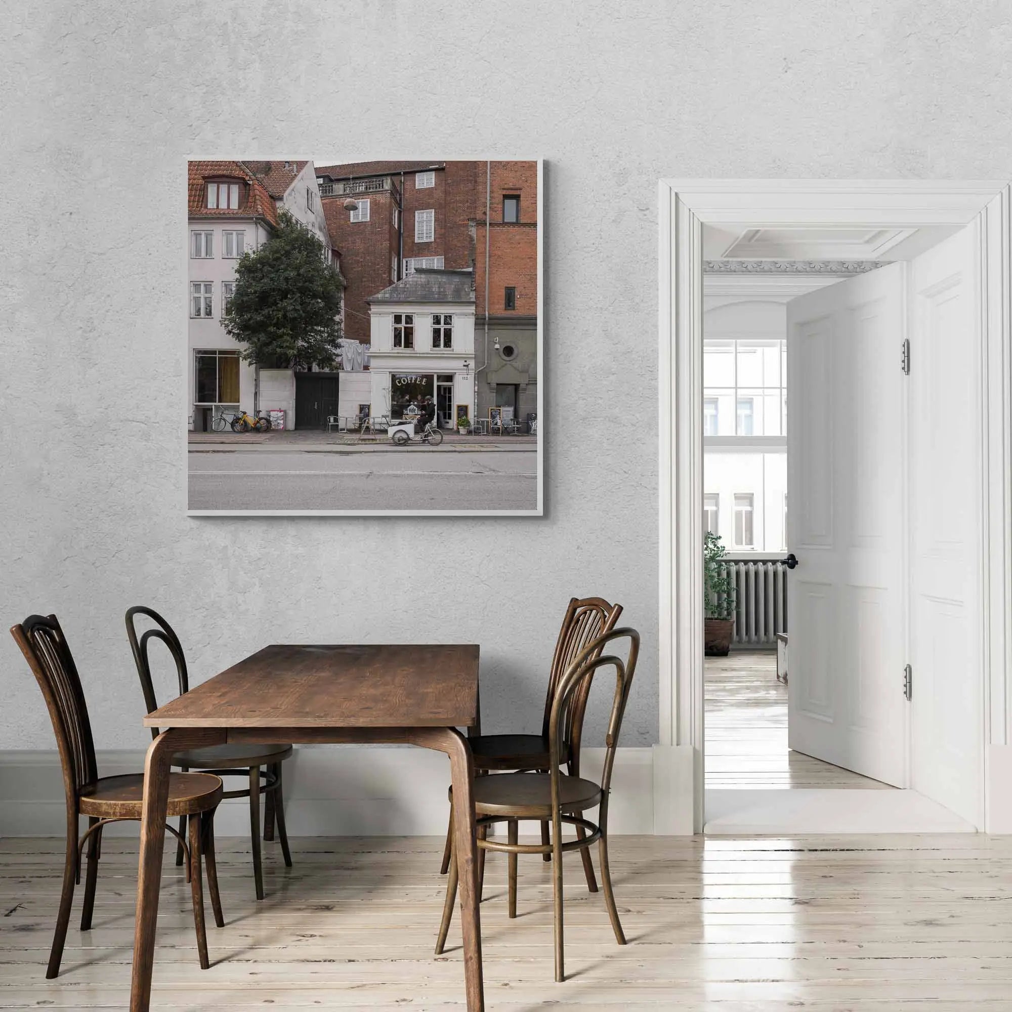 A cozy café sits nestled between classic Copenhagen buildings, with bicycles parked outside, invoking the city's relaxed urban atmosphere.