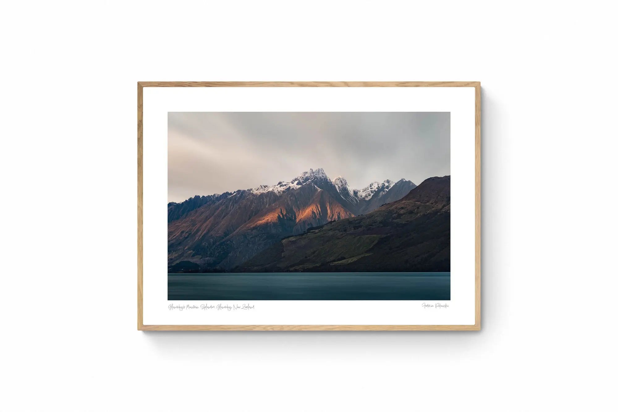 Last light of dusk casting a warm glow on the snowy peaks of mountains in Glenorchy, New Zealand, with a calm lake in the foreground.