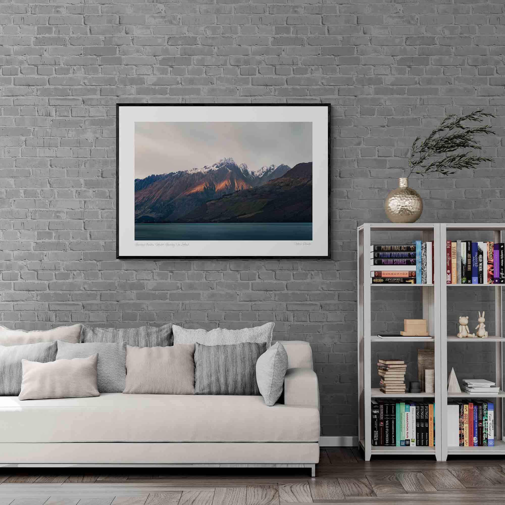 Last light of dusk casting a warm glow on the snowy peaks of mountains in Glenorchy, New Zealand, with a calm lake in the foreground.