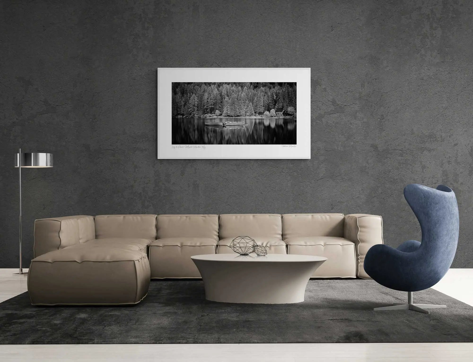 Black and white image of Lago di Braies with still water, reflective boats, a small chapel, and dense trees in the background.