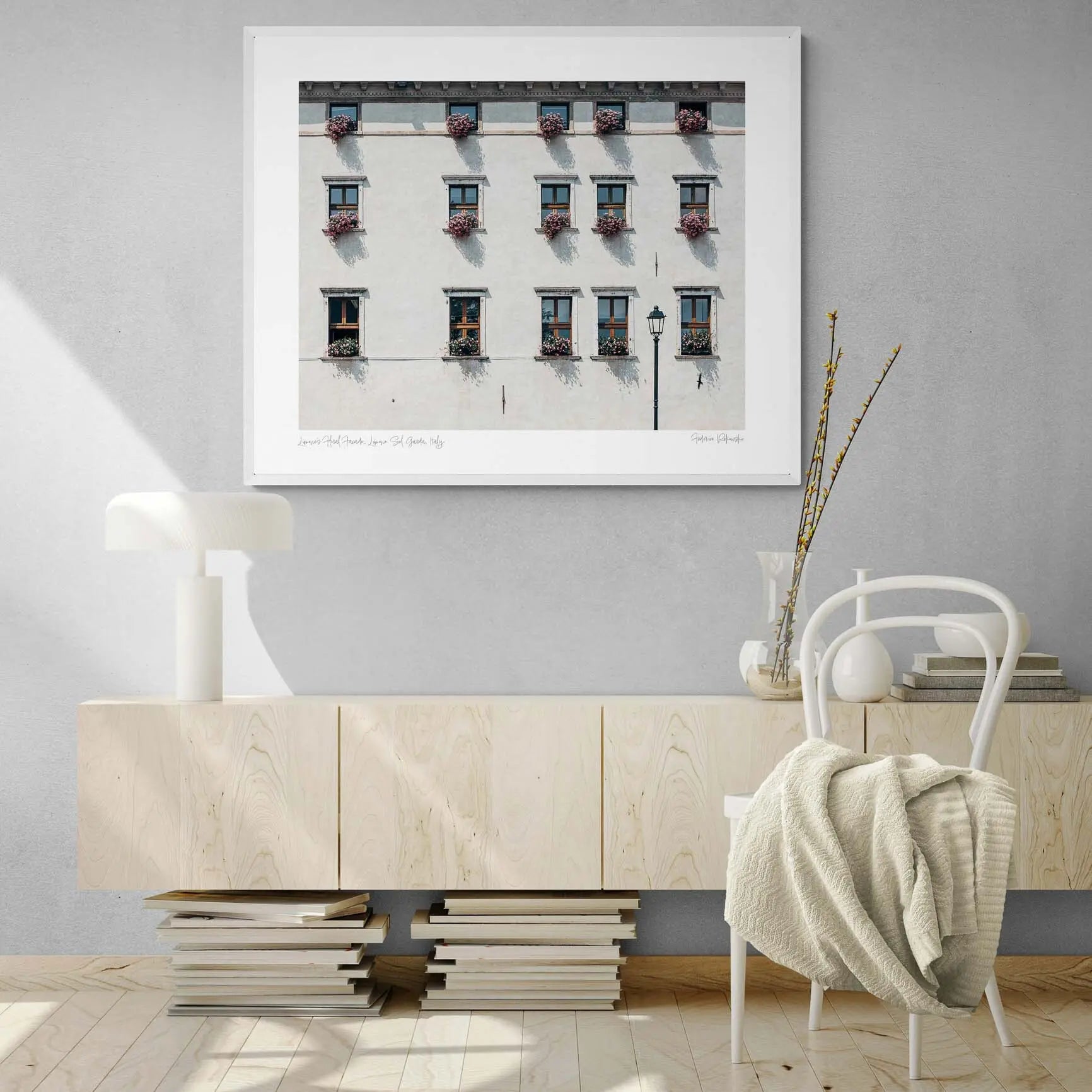 Facade of an Italian building adorned with multiple windows, each accented with vibrant pink flowers in Limone, Italy.