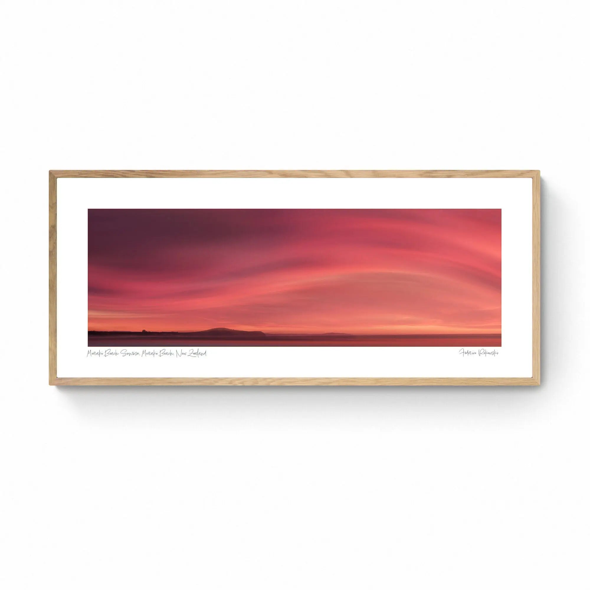 Sunrise over Moeraki Beach depicted in a photograph, showcasing vibrant red and pink clouds stretched across the sky.