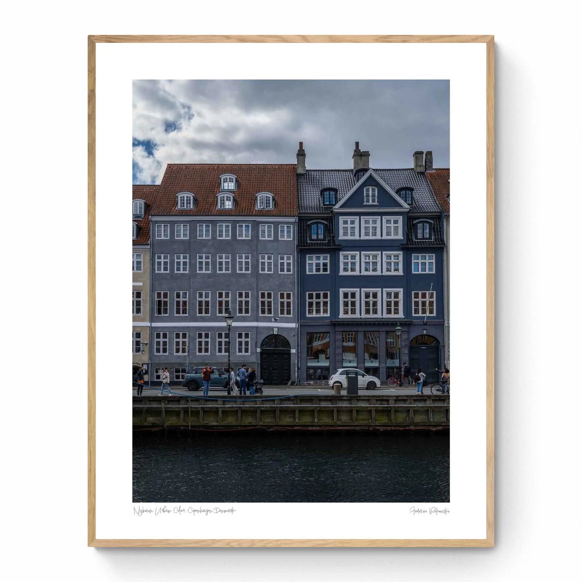 Colorful buildings along the Nyhavn canal in Copenhagen, with people walking and bikes lining the harborside.