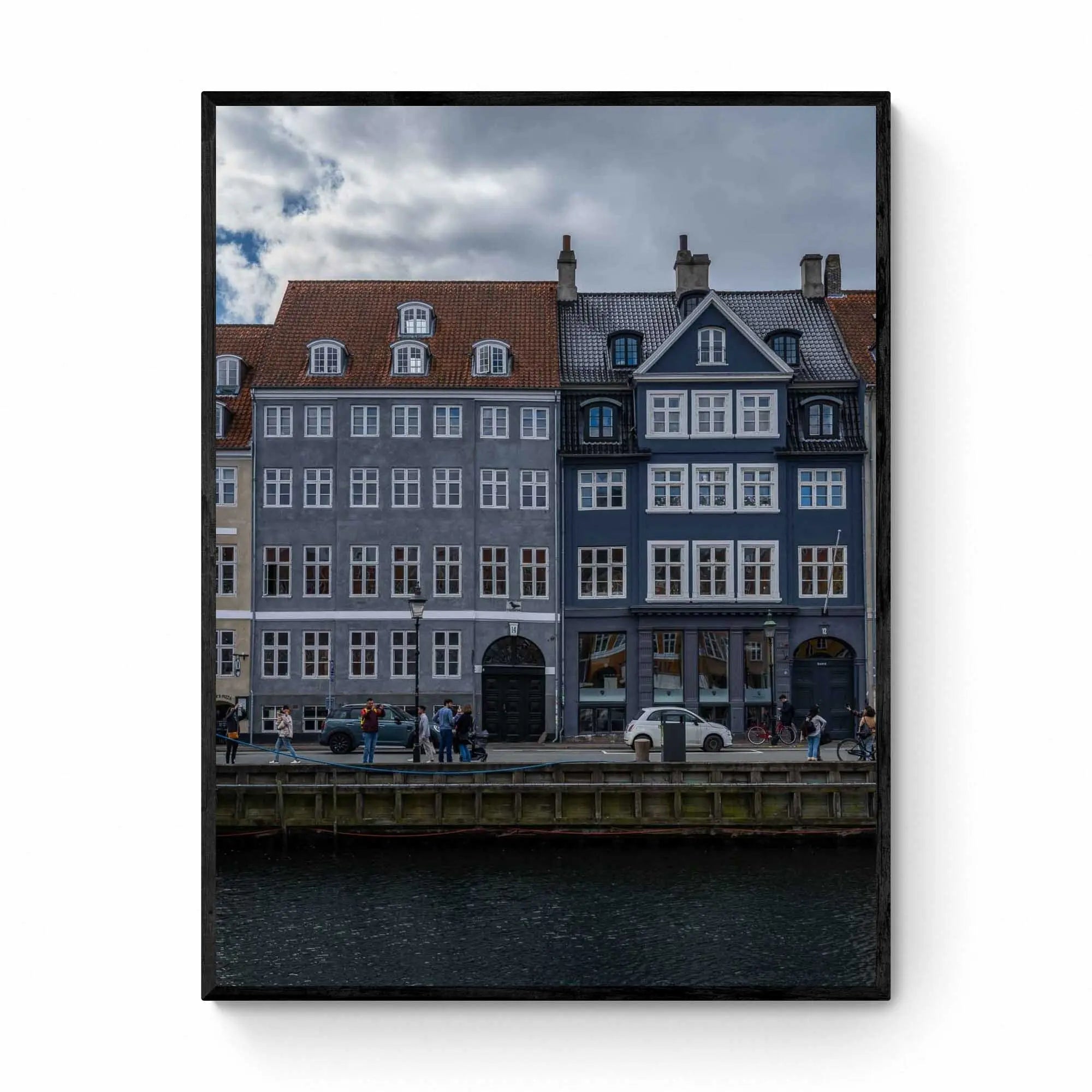 Colorful buildings along the Nyhavn canal in Copenhagen, with people walking and bikes lining the harborside.