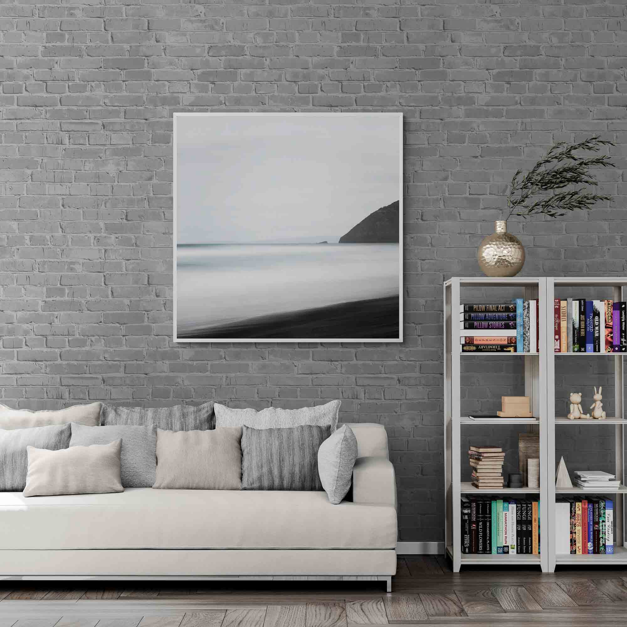 A minimalist long exposure photo of the calm sea meeting the dark sands of St. Clair's Beach in New Zealand, with a headland silhouette on the right.