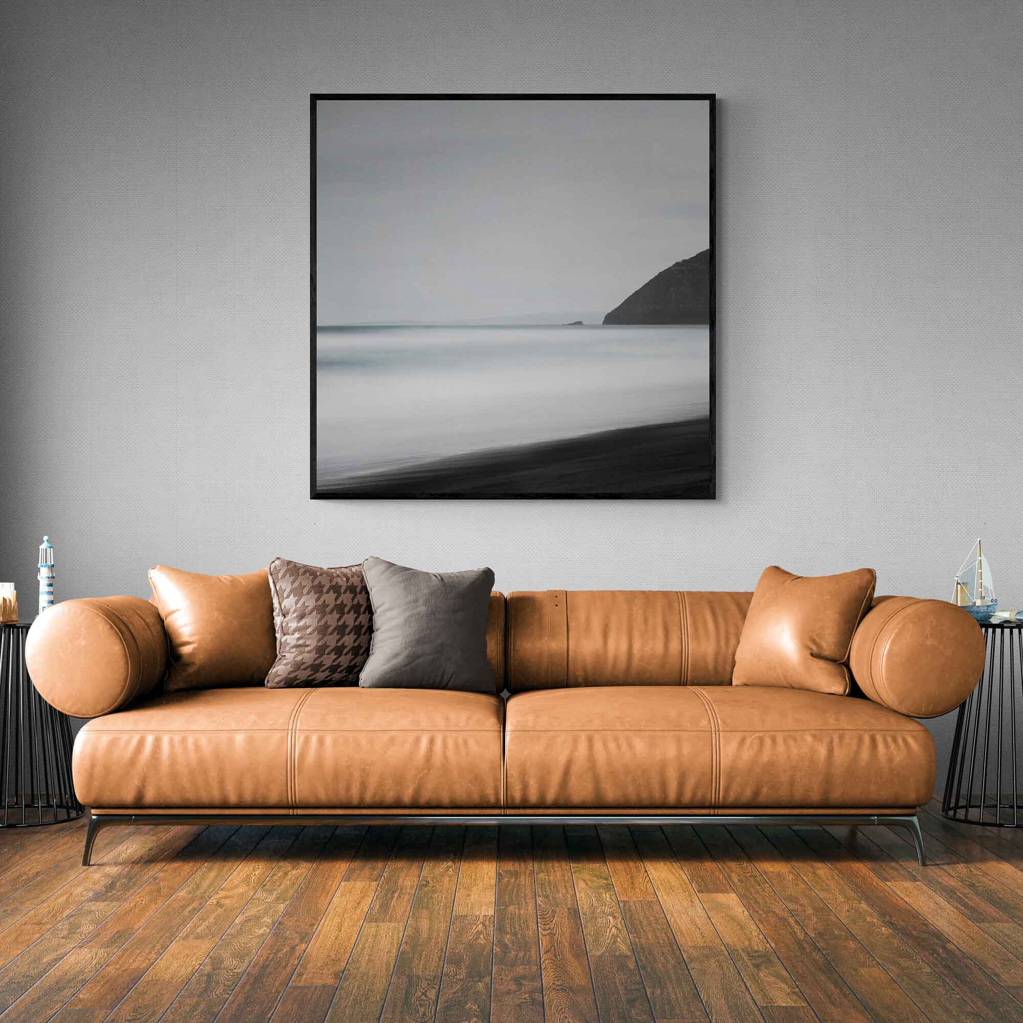 A minimalist long exposure photo of the calm sea meeting the dark sands of St. Clair's Beach in New Zealand, with a headland silhouette on the right.