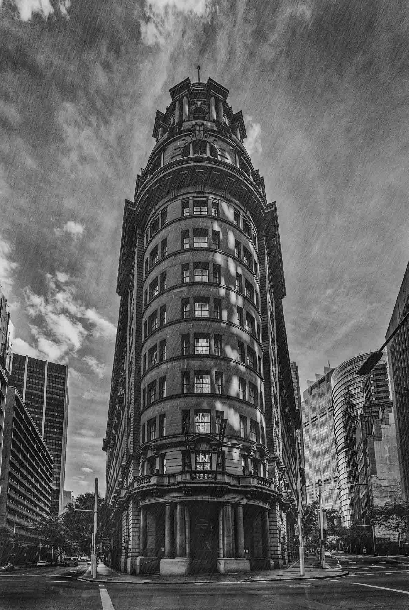 Black and white photo of an ornate, historic building in Sydney, Australia, with a dramatic sky in the background.