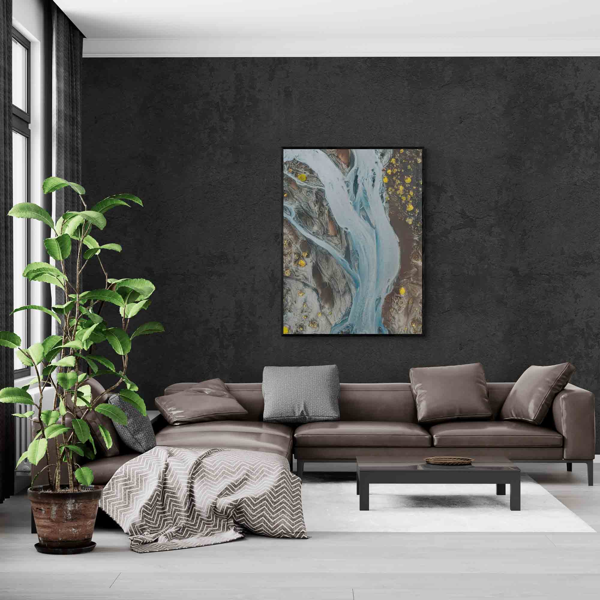 Aerial photo of a ghostly pale blue river snaking through the darker earth in Iceland, with patches of bright yellow flora.