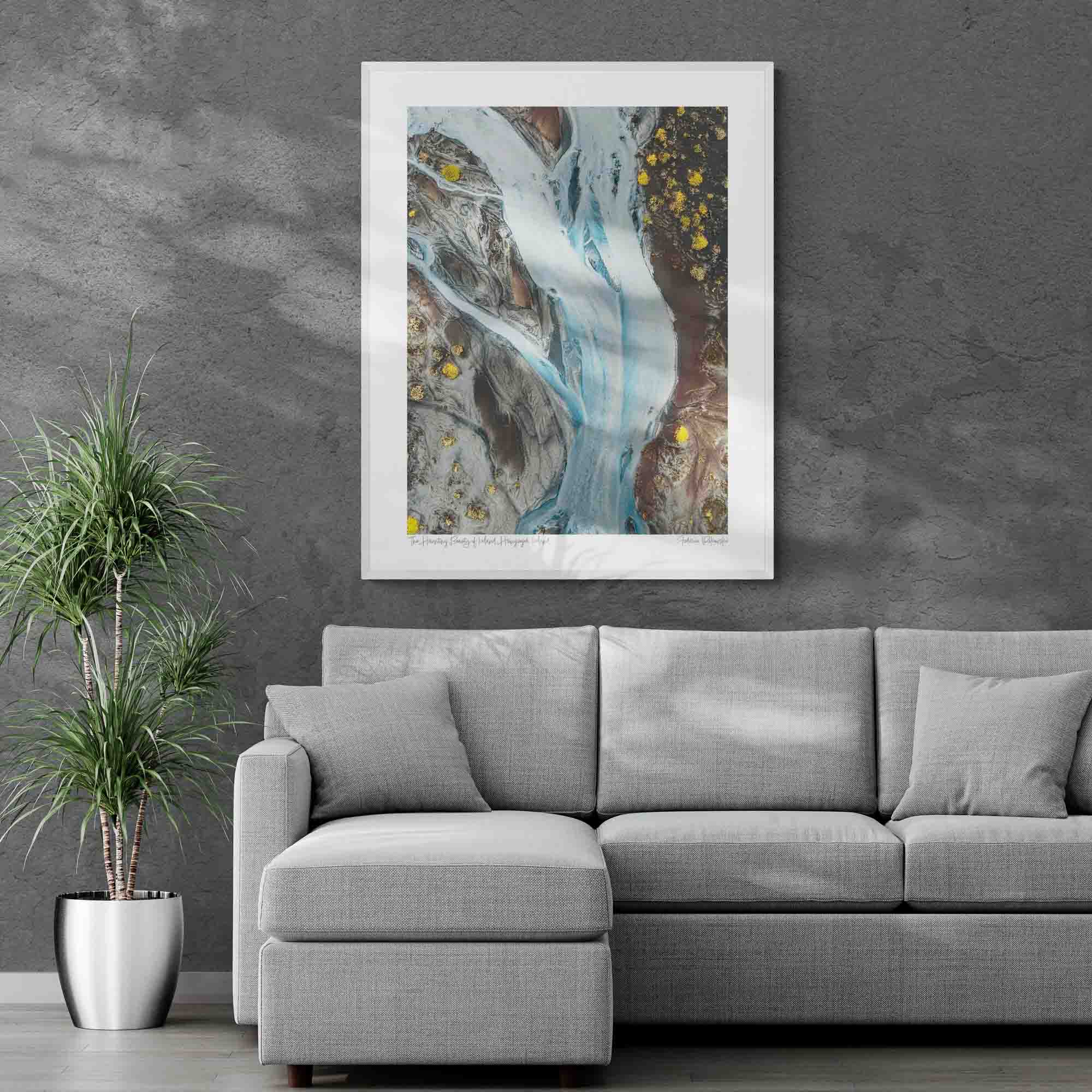 Aerial photo of a ghostly pale blue river snaking through the darker earth in Iceland, with patches of bright yellow flora.