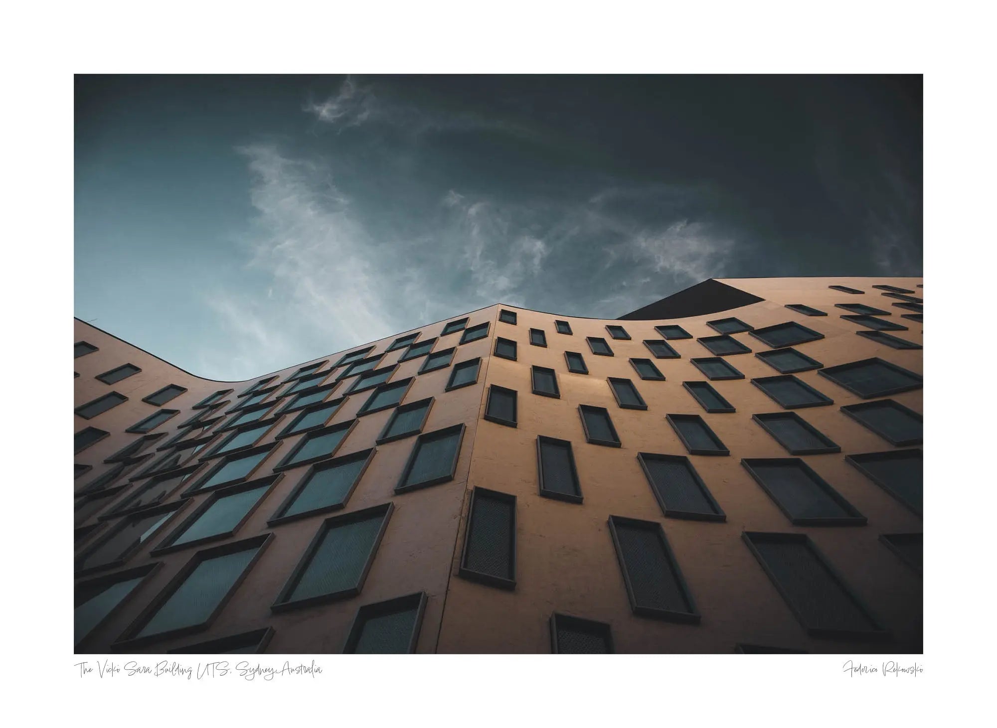 The distinctive exterior of the Vicki Sara Building at UTS, featuring a unique pattern of windows, set against the backdrop of a clear sky.