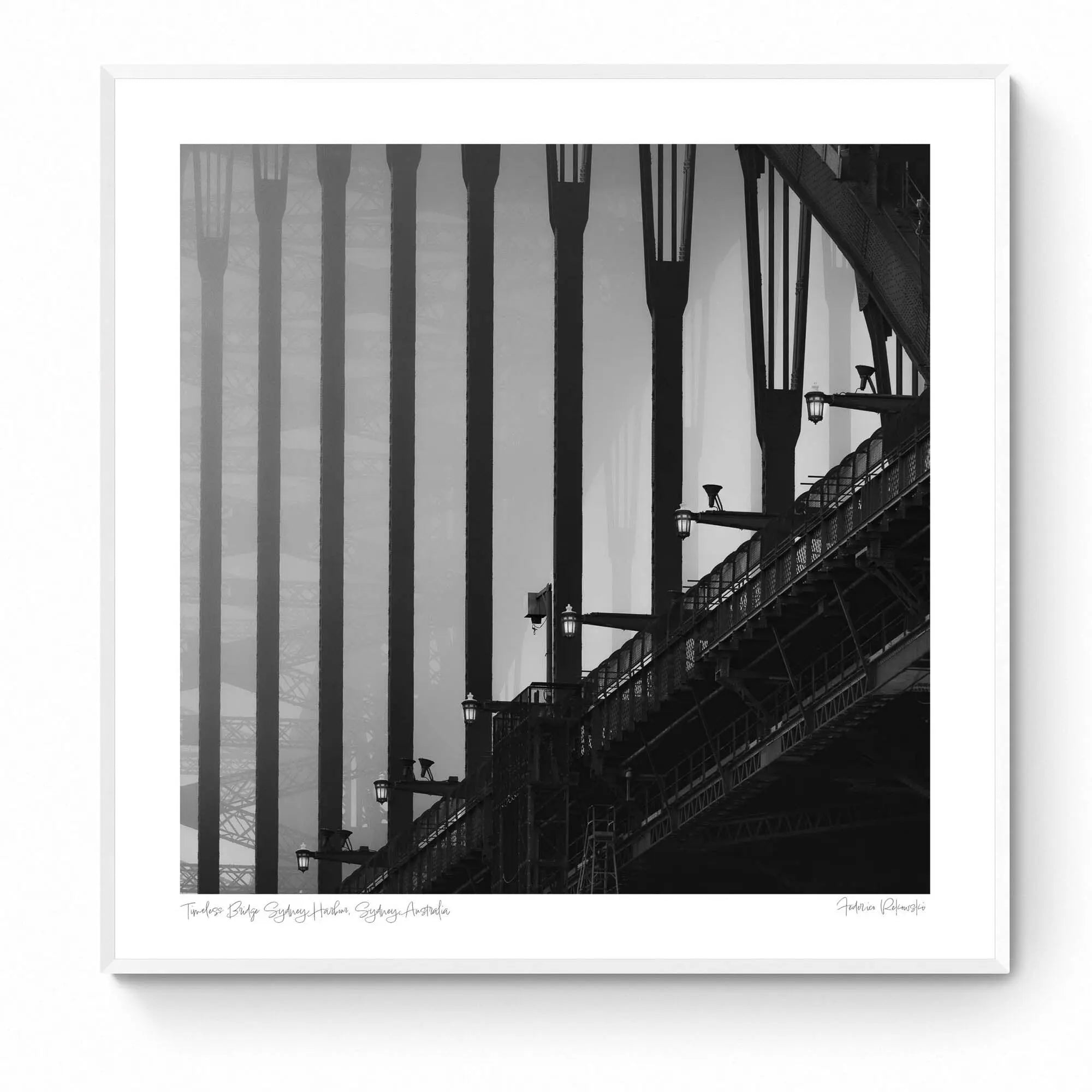 Monochrome image of Sydney Harbour Bridge, showing the contrast of the stark, strong lines of its arches and street lamps against the light sky.