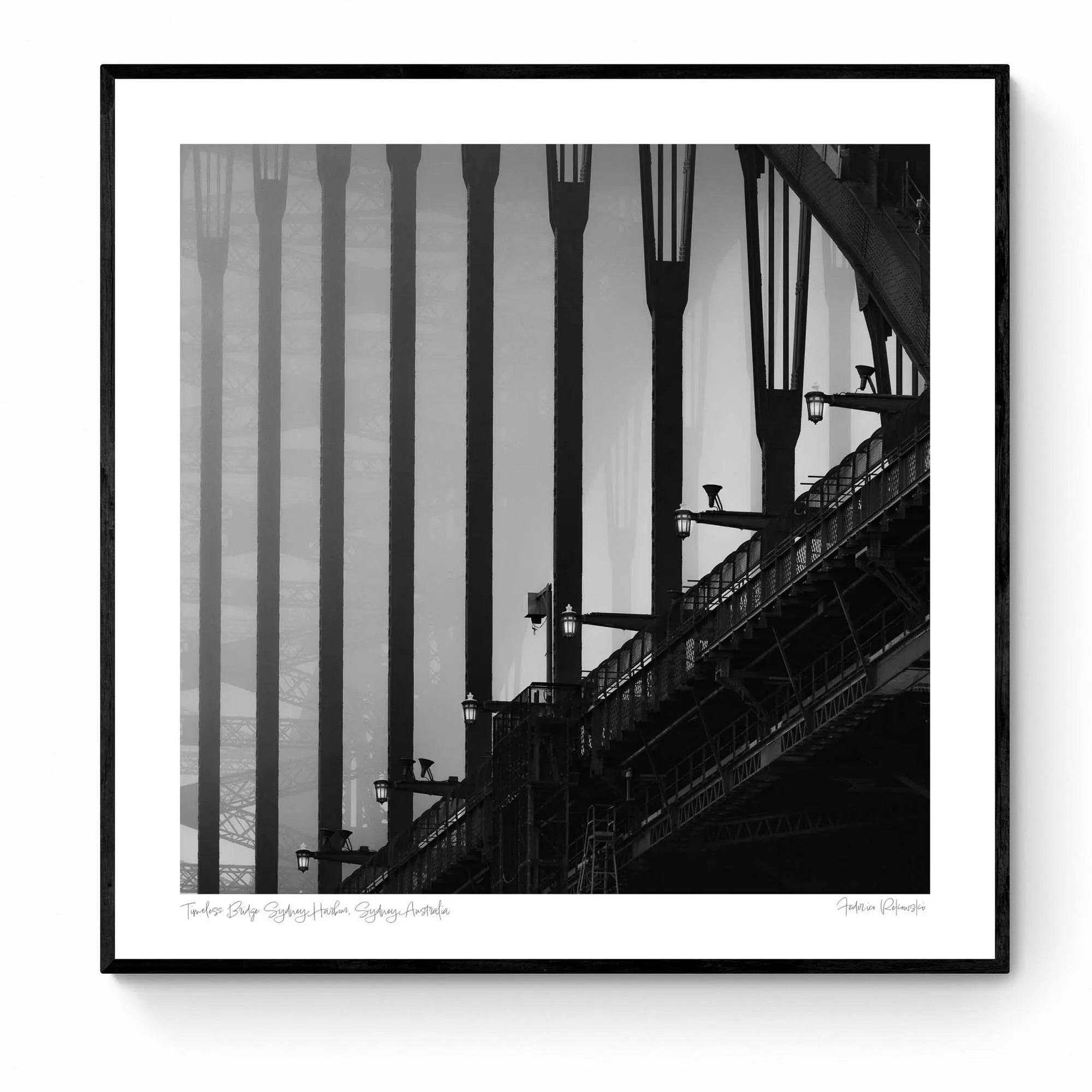 Monochrome image of Sydney Harbour Bridge, showing the contrast of the stark, strong lines of its arches and street lamps against the light sky.