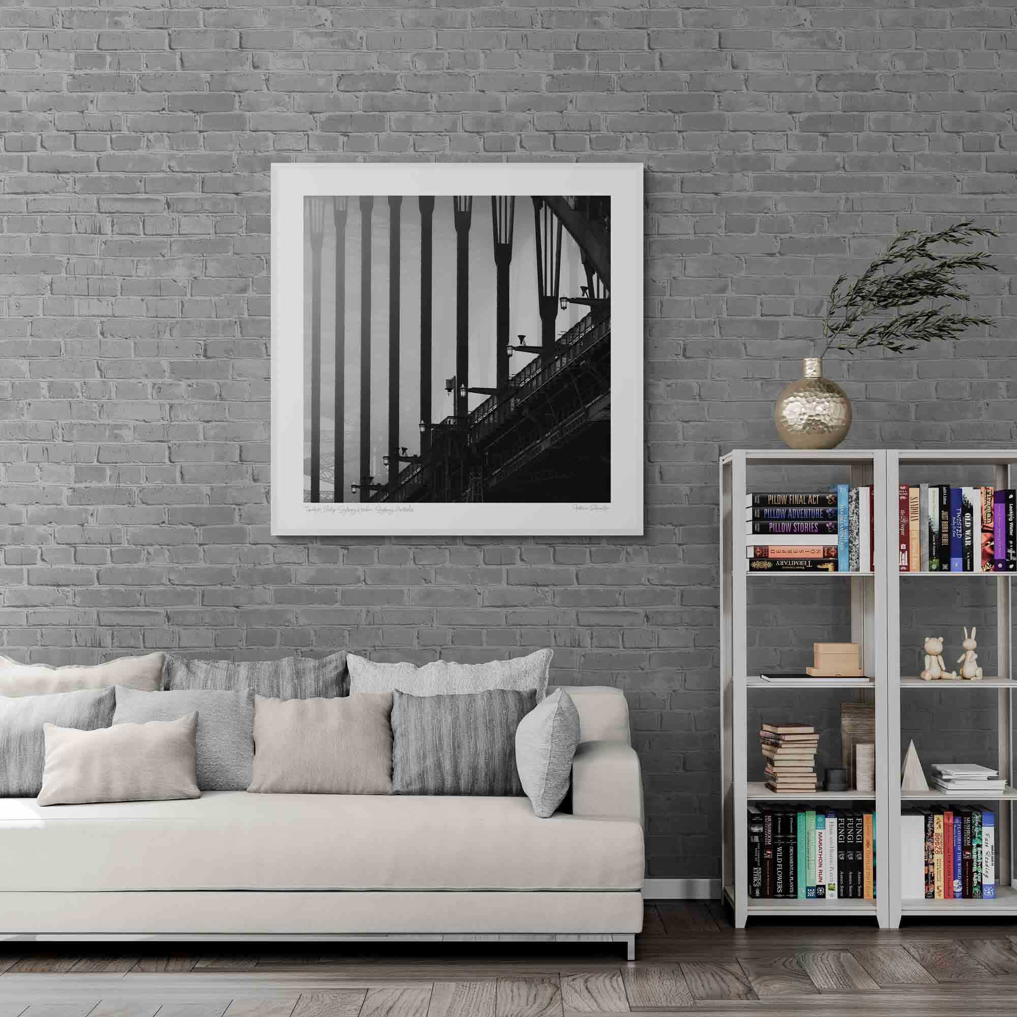 Monochrome image of Sydney Harbour Bridge, showing the contrast of the stark, strong lines of its arches and street lamps against the light sky.