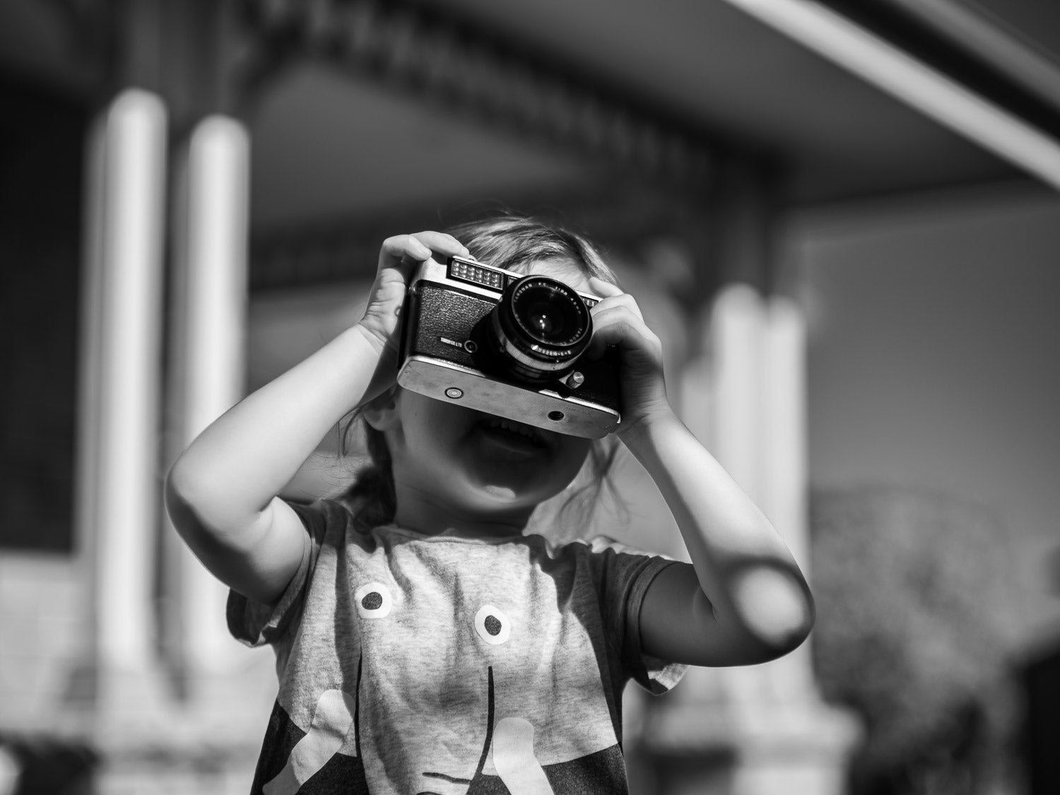 Black and white image of a girl holding a vintage camera