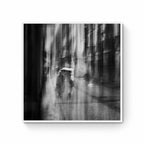 Black and white image of blurred figures under an umbrella on a rainy street in San Sebastian, Spain, creating an ethereal atmosphere.