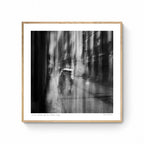Black and white image of blurred figures under an umbrella on a rainy street in San Sebastian, Spain, creating an ethereal atmosphere.