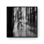Black and white image of blurred figures under an umbrella on a rainy street in San Sebastian, Spain, creating an ethereal atmosphere.
