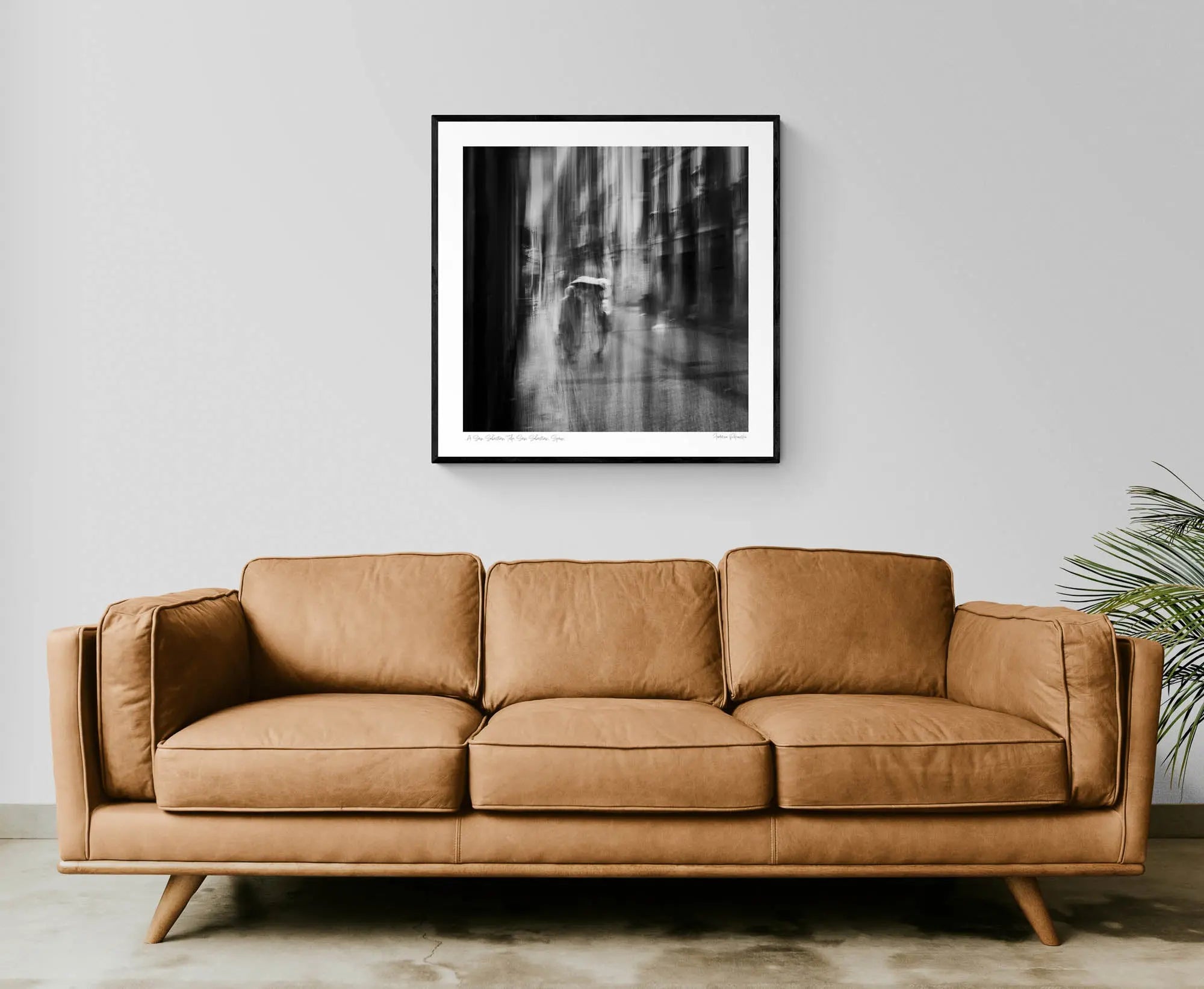 Black and white image of blurred figures under an umbrella on a rainy street in San Sebastian, Spain, creating an ethereal atmosphere.