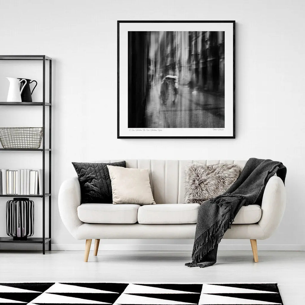 Black and white image of blurred figures under an umbrella on a rainy street in San Sebastian, Spain, creating an ethereal atmosphere.
