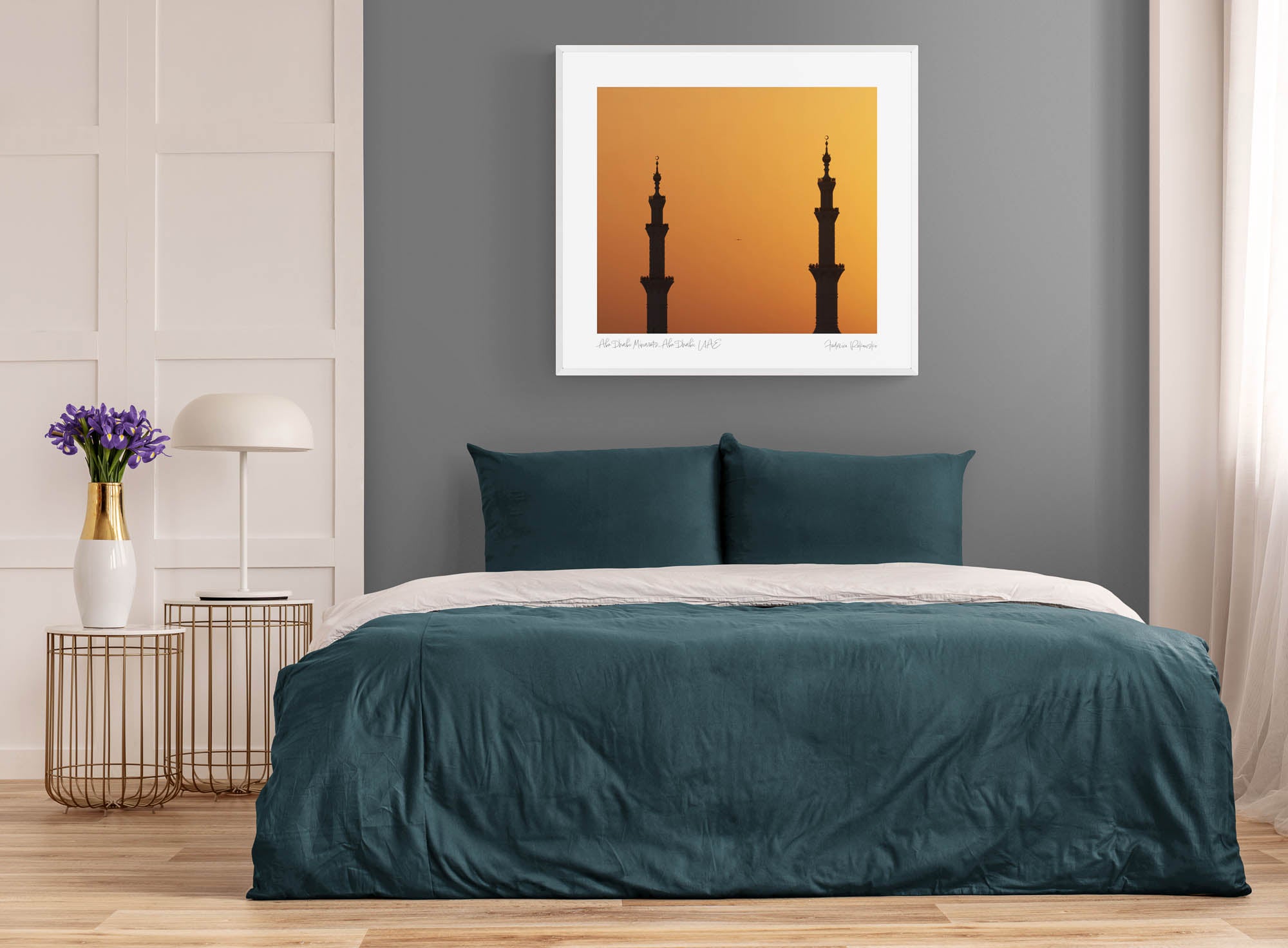 Silhouettes of two minarets against an orange sunset sky in Abu Dhabi.  Framed on a room