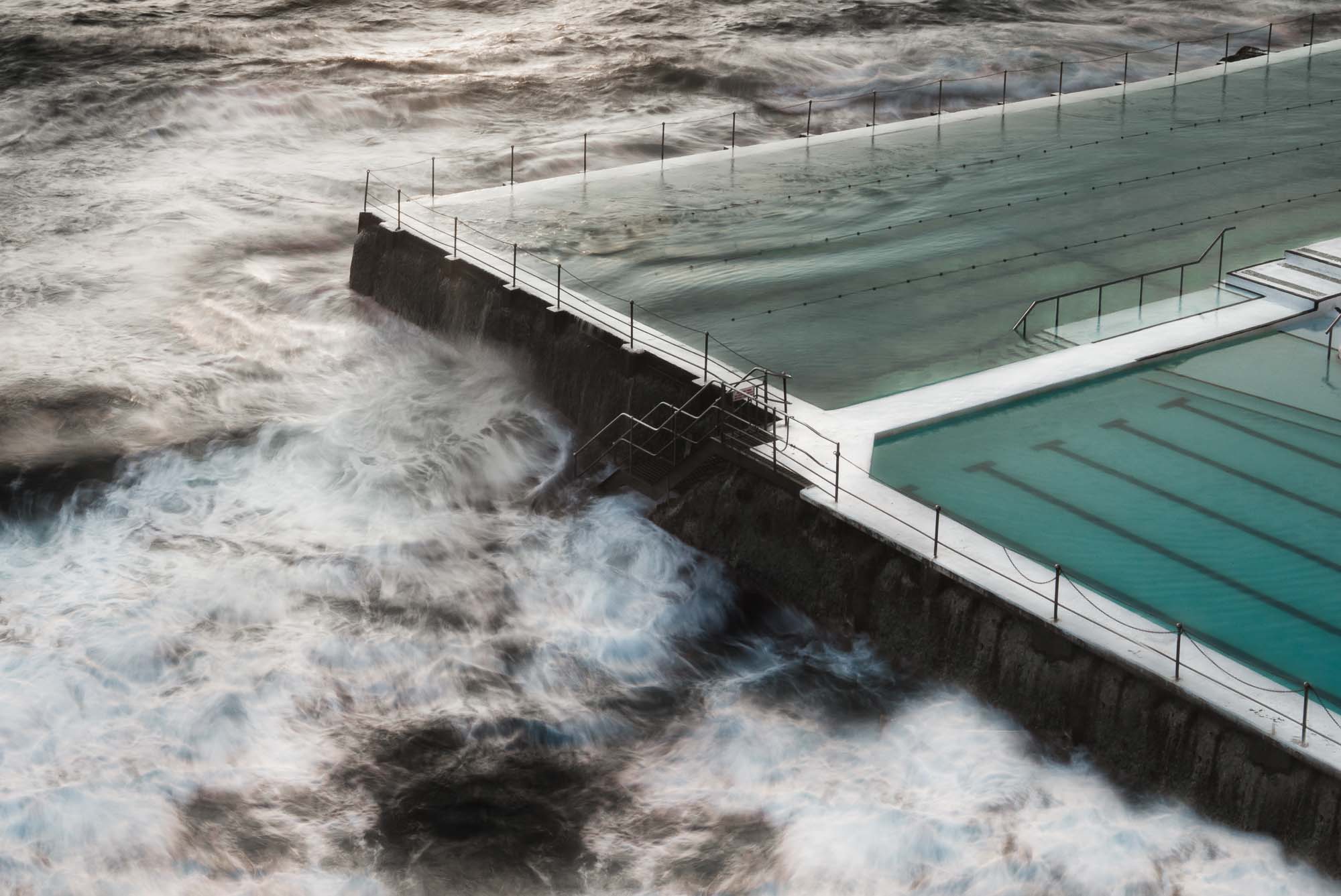 Long exposure of the Bondi Rock Pool in Sydney, with swirling ocean waves surrounding the calm waters of the pool.