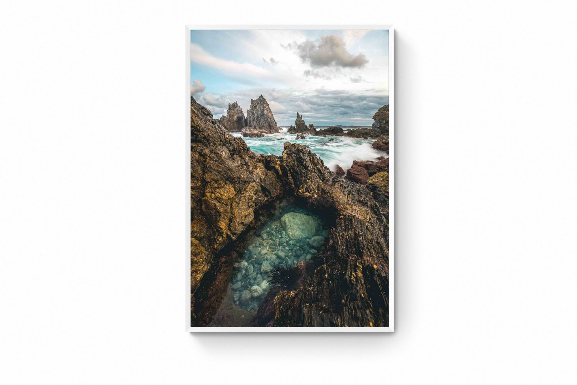 Rugged rock formations of Camel Rock in Bermagui with a natural tide pool in the foreground and turbulent sea in the background under a cloudy sky.