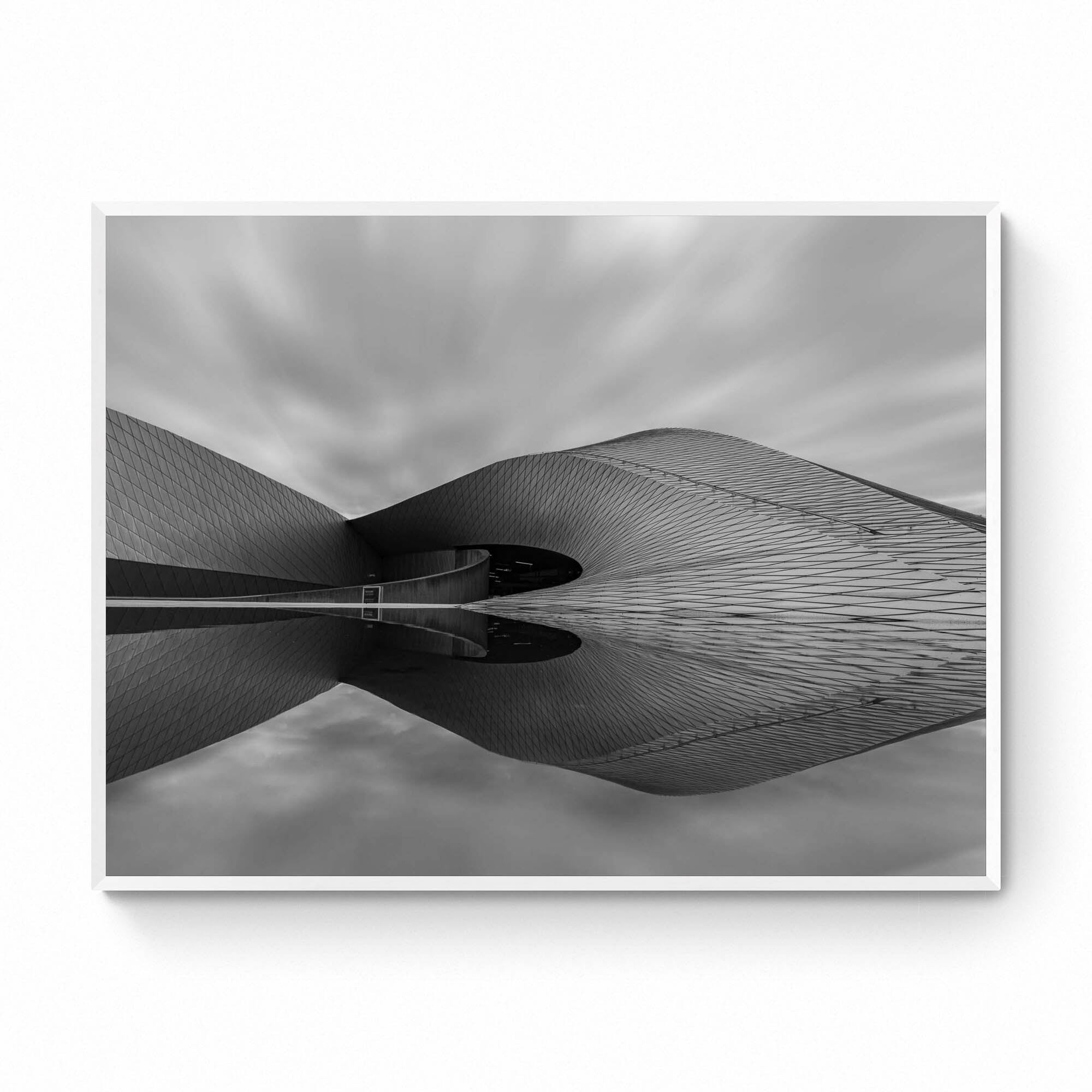 Black and white image of The Blue Planet Aquarium in Copenhagen with its reflective, wavy facade against a blurred sky.