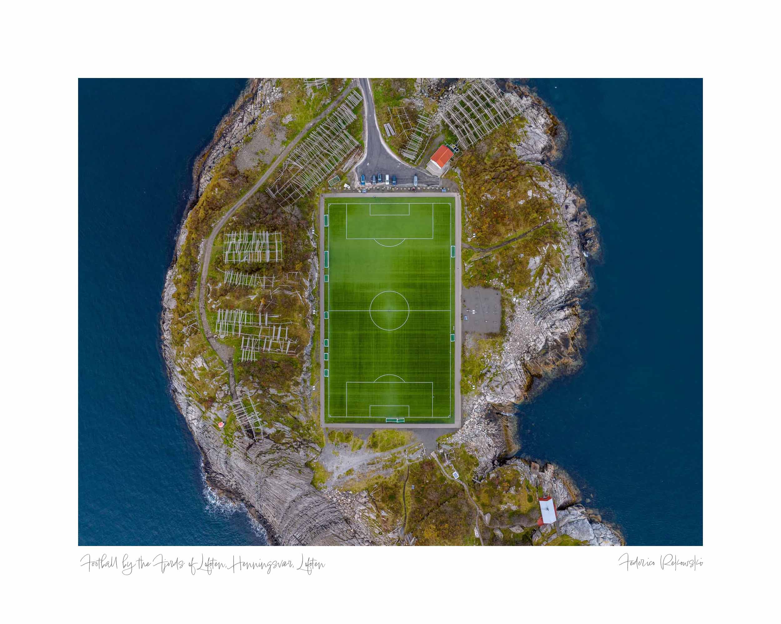 Aerial view of Henningsvær Stadium in Lofoten, Norway, with a soccer field surrounded by rocky terrain and sea.
