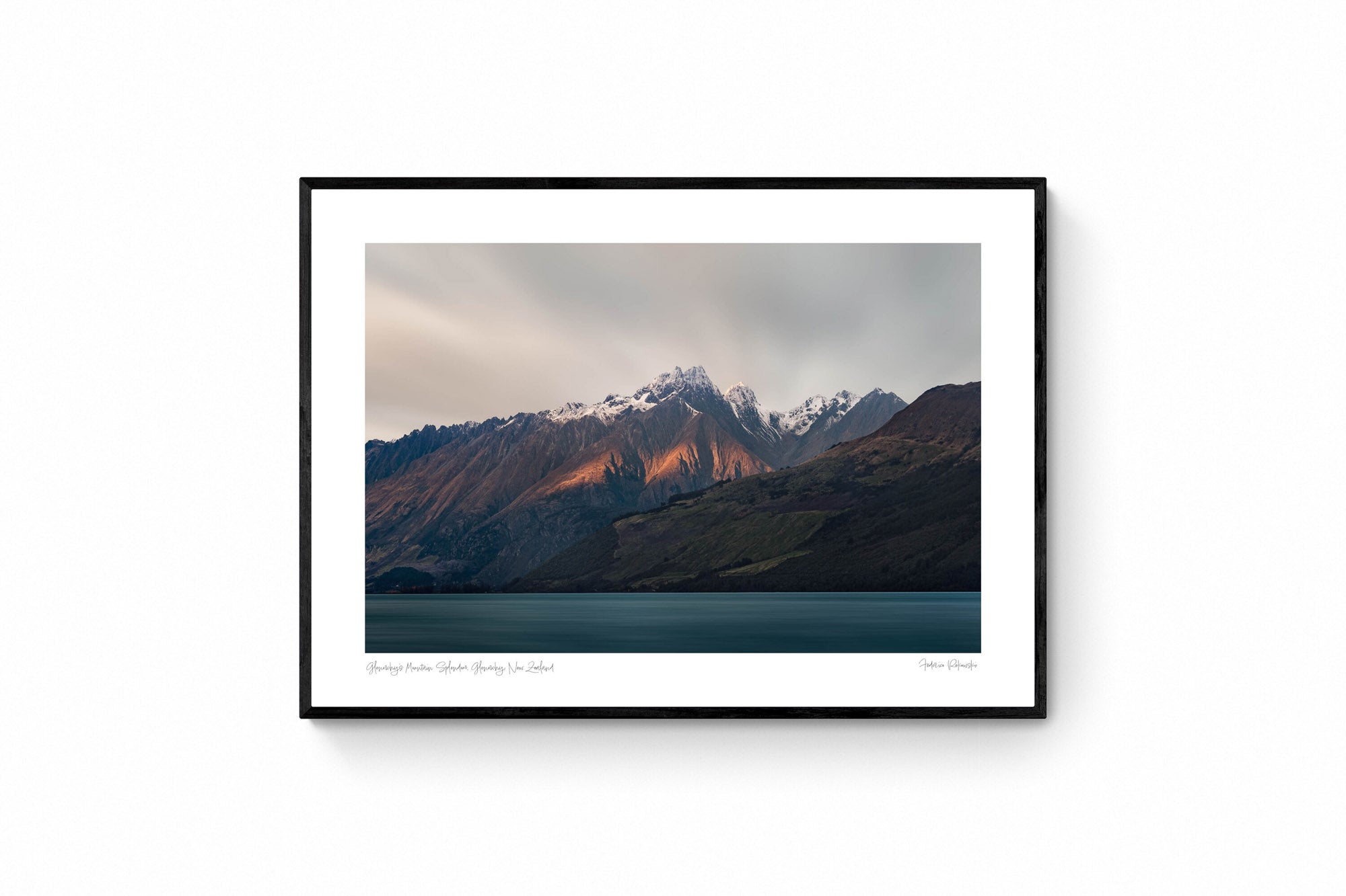 Last light of dusk casting a warm glow on the snowy peaks of mountains in Glenorchy, New Zealand, with a calm lake in the foreground.
