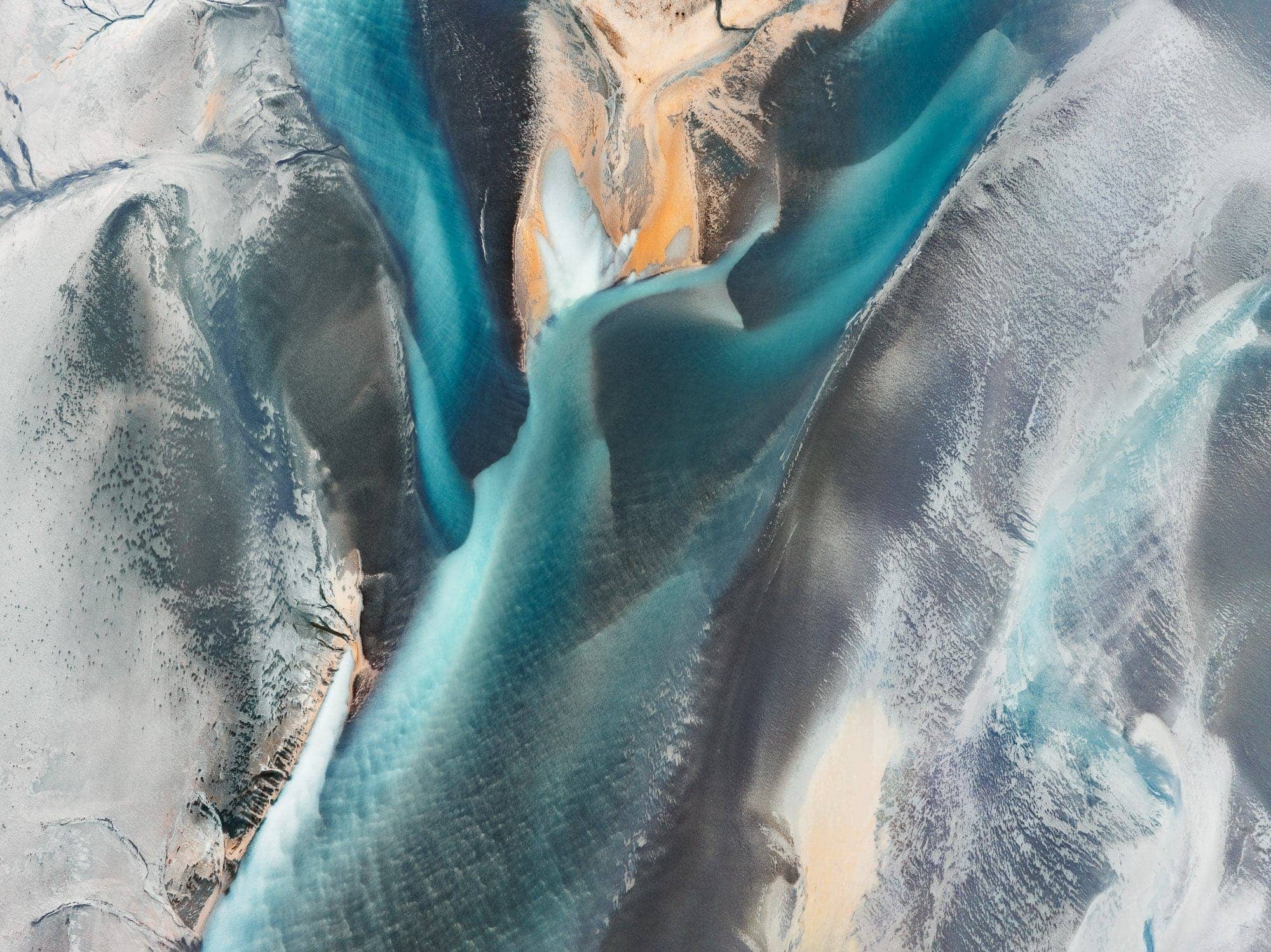 Aerial shot of the dynamic interface between water and volcanic sands near Höfn, Iceland, displaying a stunning abstract pattern.