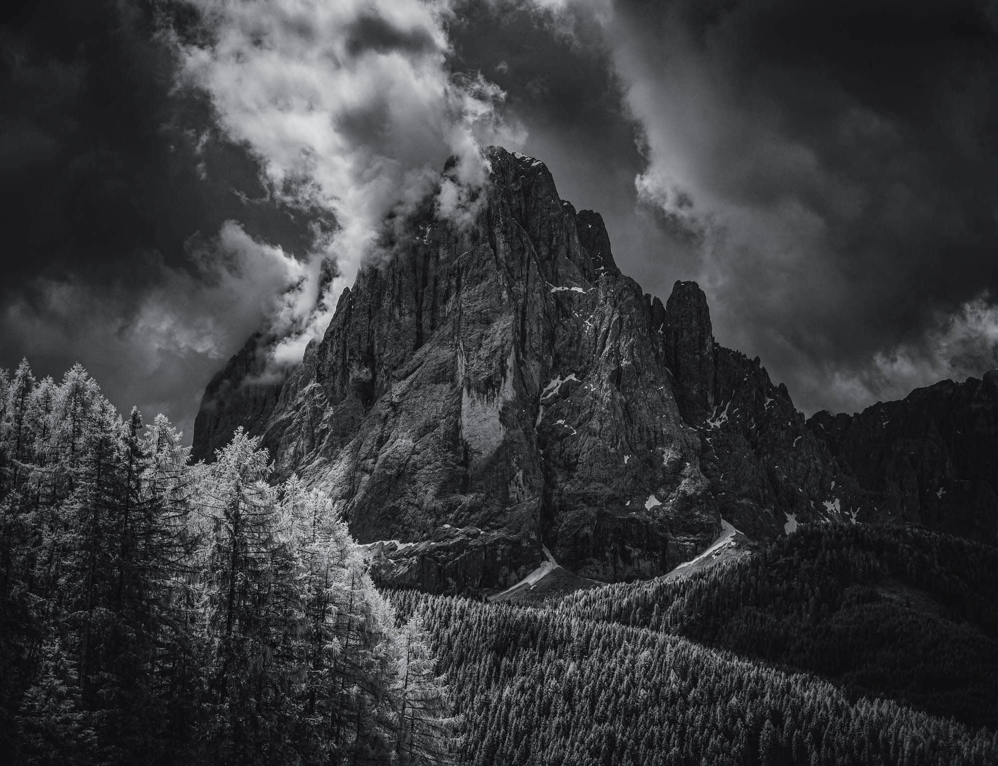Infrared black and white image of the Dolomites' rugged peaks and glowing forest, reminiscent of Ansel Adams' style.