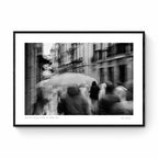 A monochrome image of pedestrians with umbrellas blurred by motion, embodying rain's lullaby in San Sebastian, inspired by Langston Hughes’ poetry.