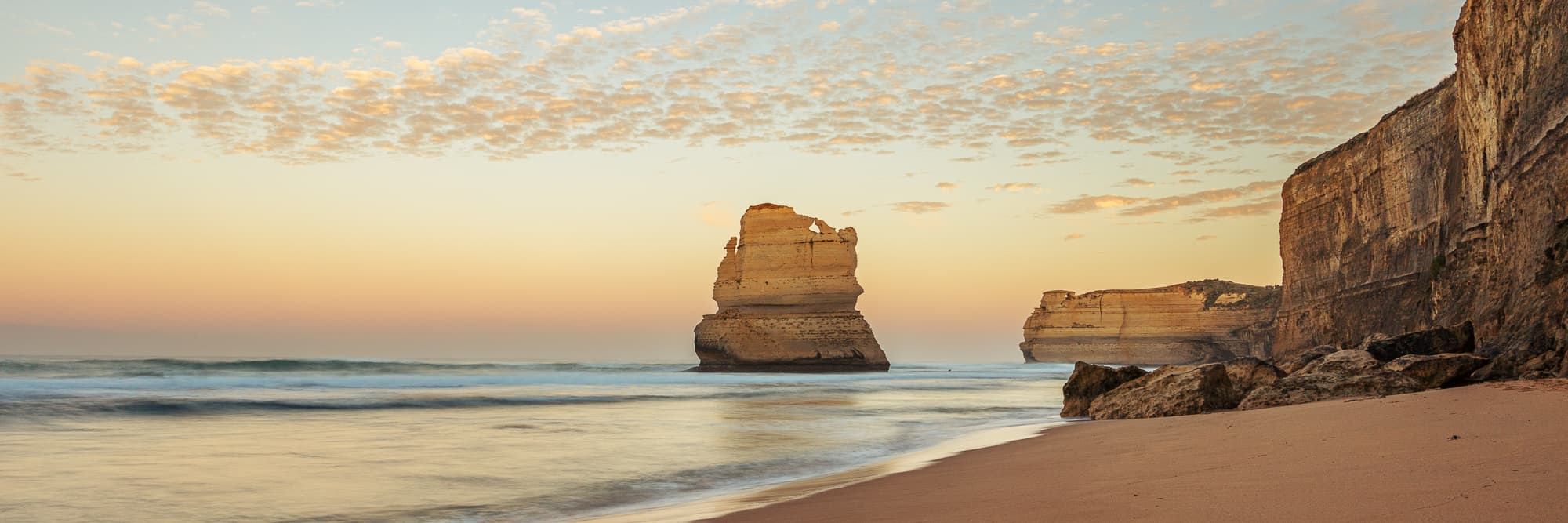 Twilight view of Gibson Steps beach with the Twelve Apostles limestone stacks against a pastel sky in Australia.