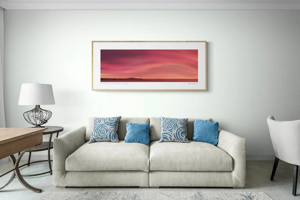 Sunrise over Moeraki Beach depicted in a photograph, showcasing vibrant red and pink clouds stretched across the sky.