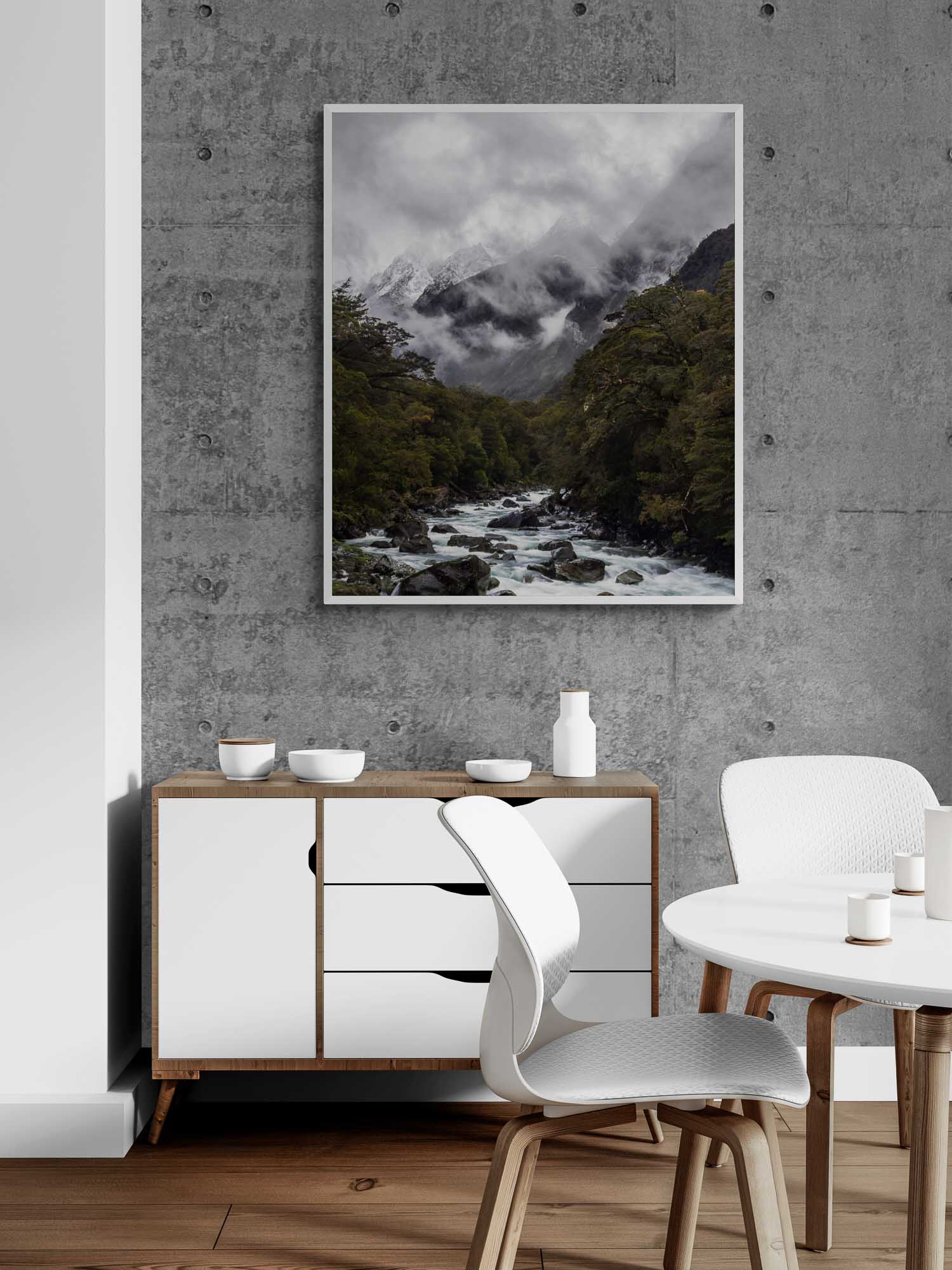 A powerful river cuts through a verdant forest with snow-covered mountains enshrouded in mist in the background at Milford Sound, New Zealand. Frame on a living Room