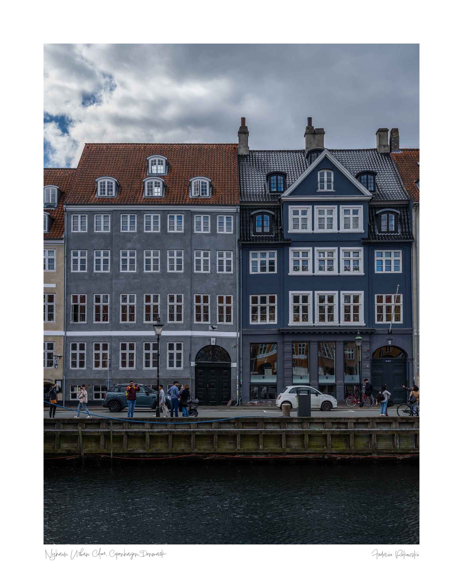 Colorful buildings along the Nyhavn canal in Copenhagen, with people walking and bikes lining the harborside.