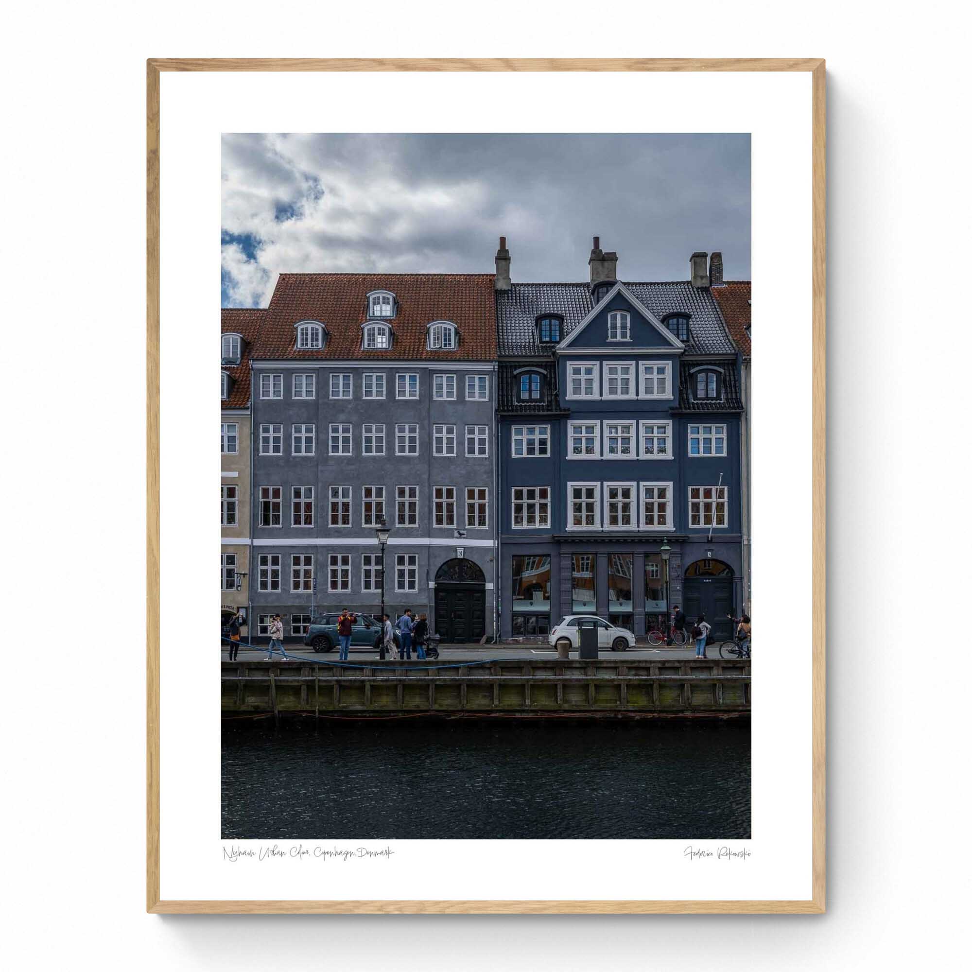 Colorful buildings along the Nyhavn canal in Copenhagen, with people walking and bikes lining the harborside.