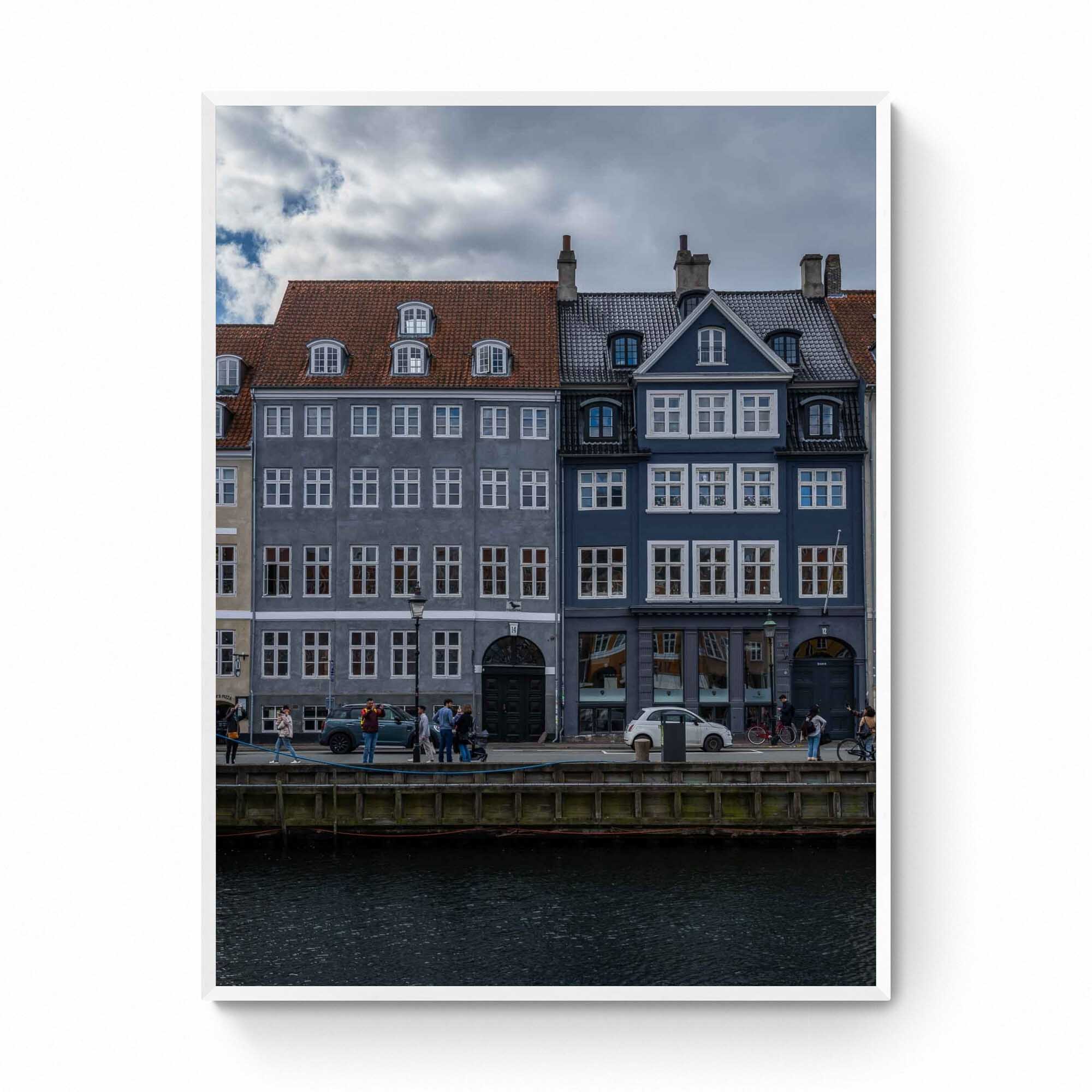 Colorful buildings along the Nyhavn canal in Copenhagen, with people walking and bikes lining the harborside.