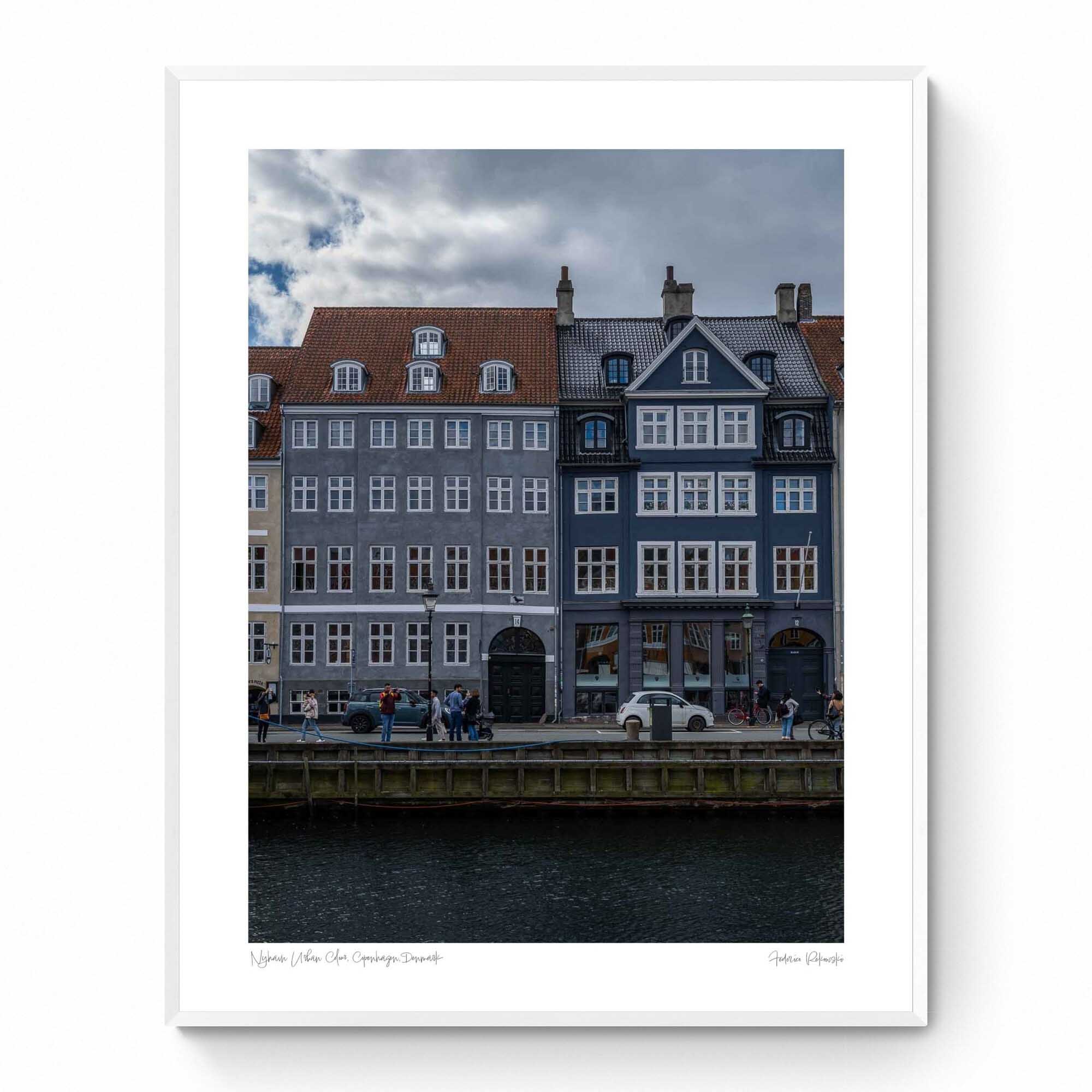 Colorful buildings along the Nyhavn canal in Copenhagen, with people walking and bikes lining the harborside.