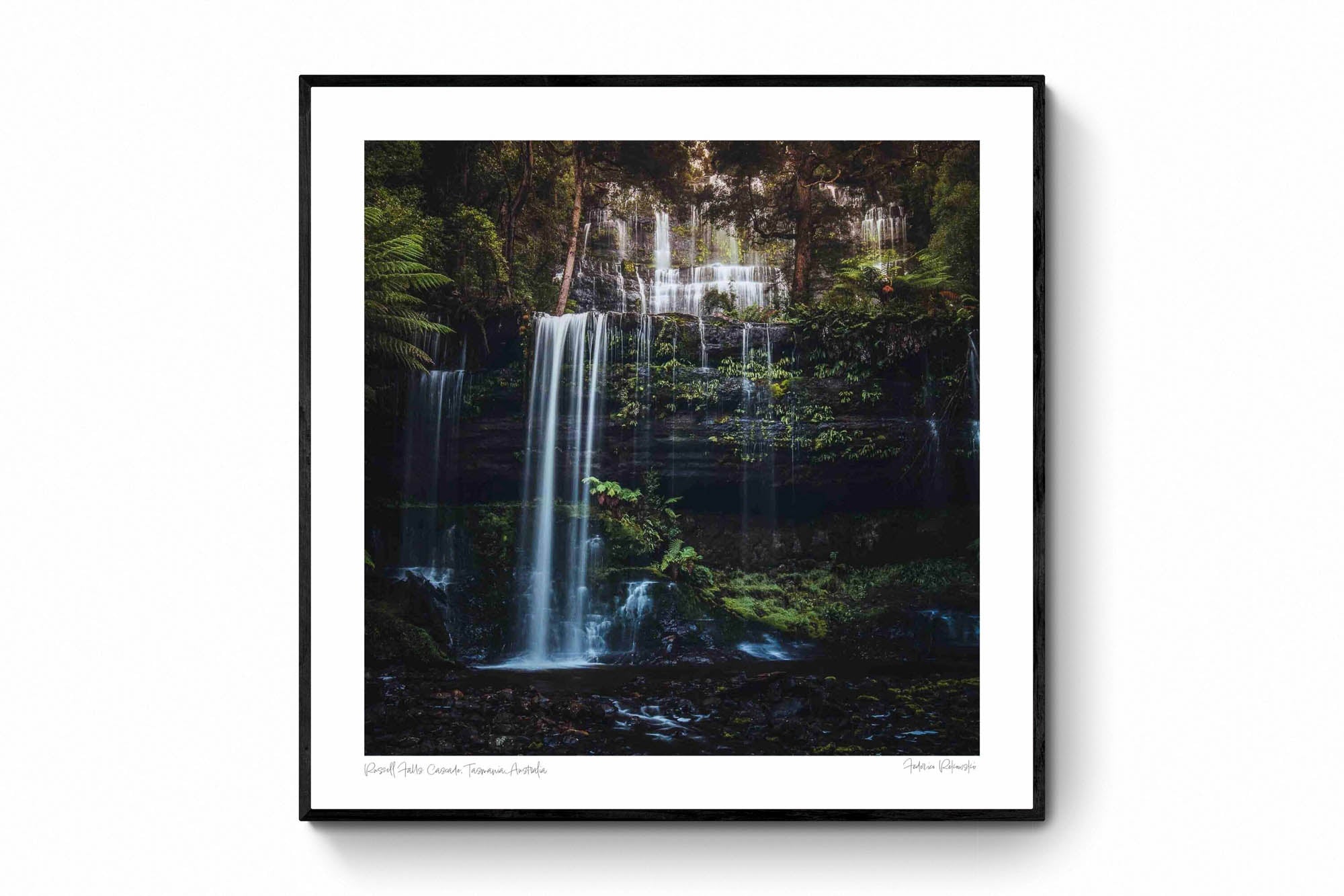 Long exposure photo of the multi-tiered Russell Falls in Tasmania, surrounded by a lush, fern-draped forest.