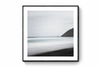 A minimalist long exposure photo of the calm sea meeting the dark sands of St. Clair's Beach in New Zealand, with a headland silhouette on the right.