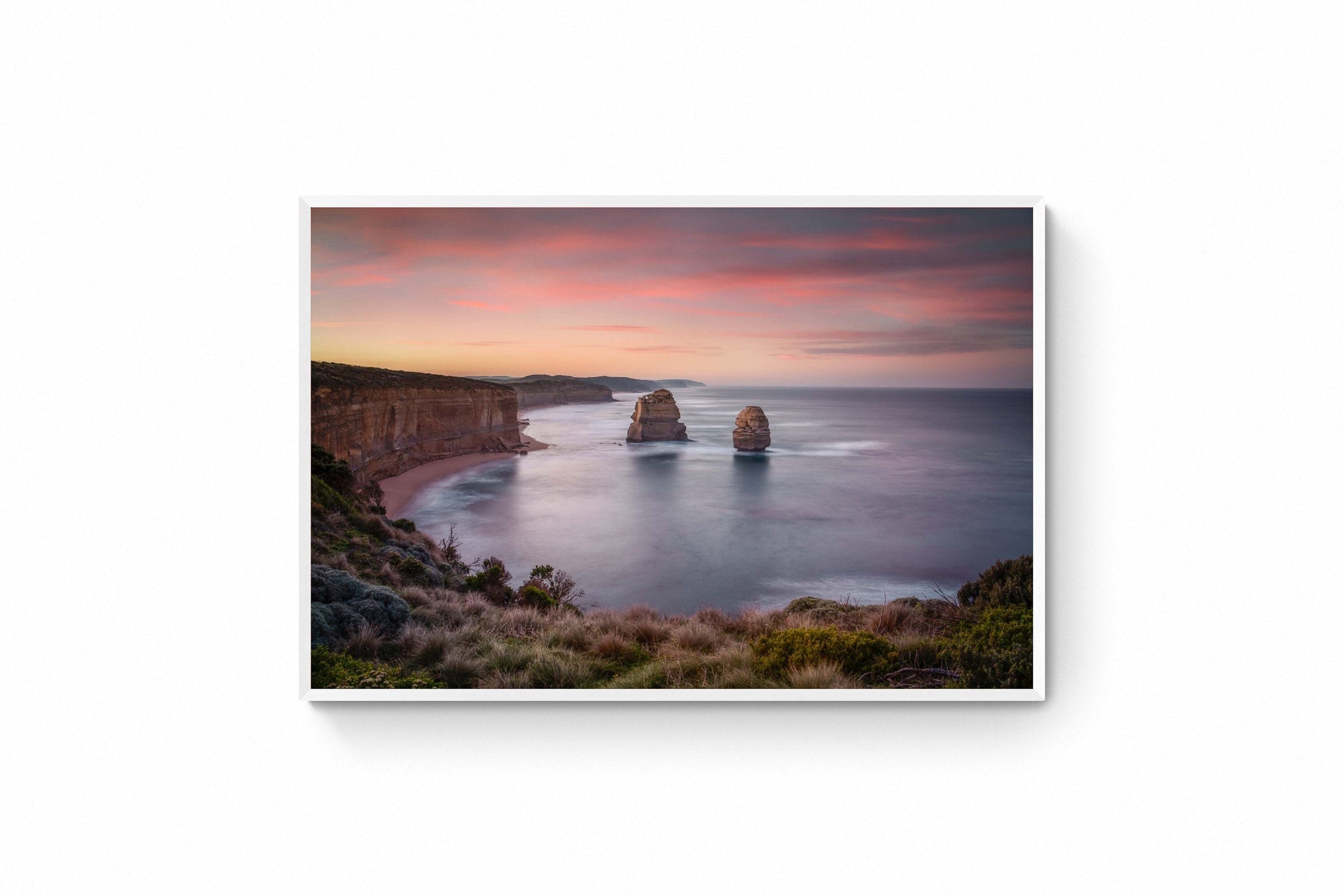 Sunset at The Twelve Apostles, with smooth seas and pastel skies highlighting the limestone formations off Australia's coast.