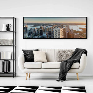 Panoramic view of Sydney Harbour at sunrise, with sunlight bathing the cityscape and water in golden hues.