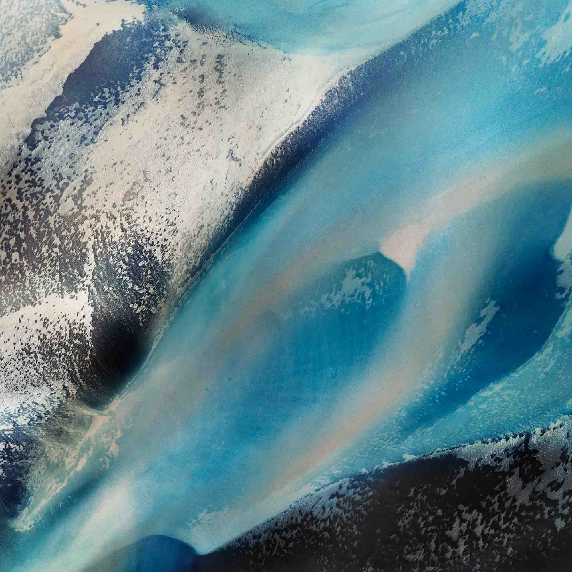 Overhead shot of contrasting blue glacial streams and ashy mountain terrain in an abstract Icelandic landscape.