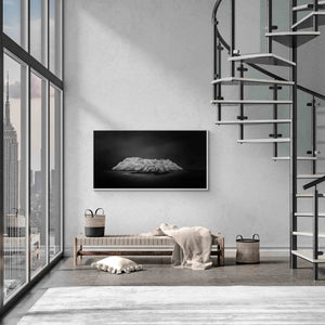 "Black and white image of an isolated island in San Sebastian, Spain, with radiant white foliage under a dark sky."