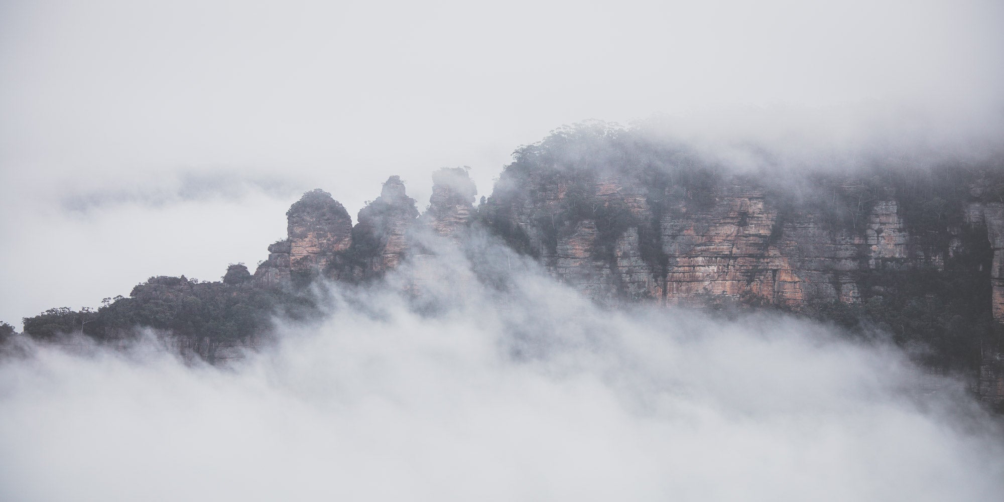 The Three Sisters rock formation in Sydney, Australia, is enshrouded in mist, as viewed from Sublime Point.
