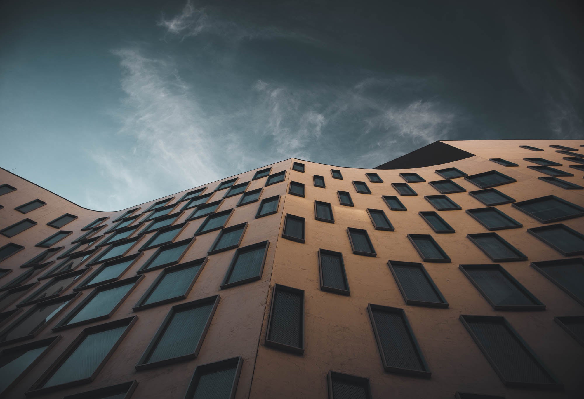 The distinctive exterior of the Vicki Sara Building at UTS, featuring a unique pattern of windows, set against the backdrop of a clear sky.