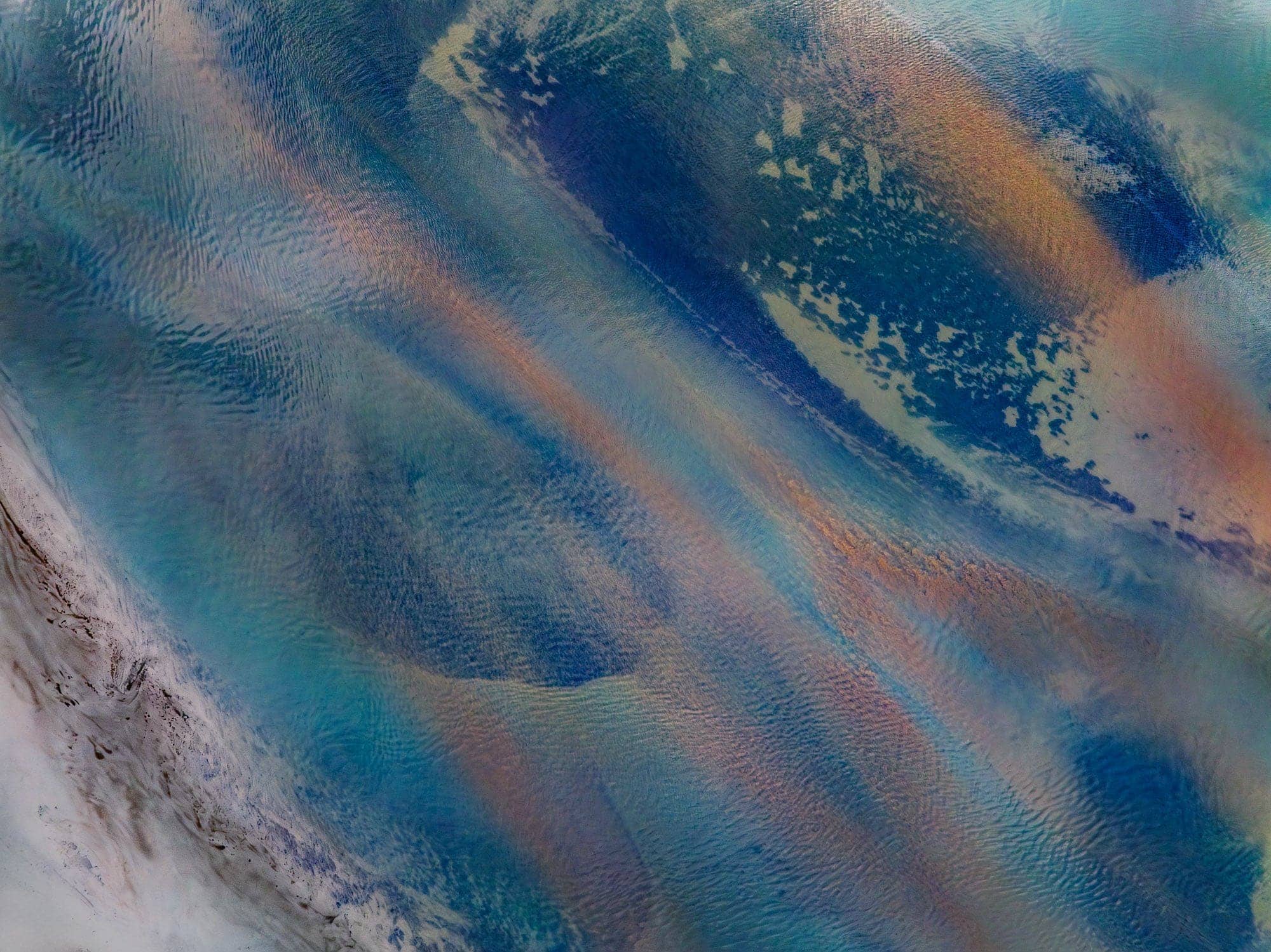 Aerial photo of Fjord di Papós, Iceland, with intricate patterns and a spectrum of colors resembling an abstract watercolor painting.